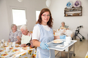 Undersköterska serverar mat på äldreboende